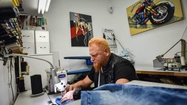 Mihai, croitor la Croitorie Mihai, lucrând la o pereche de blugi în atelier